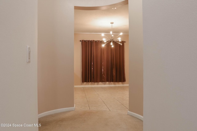 hall with light tile patterned flooring and a chandelier