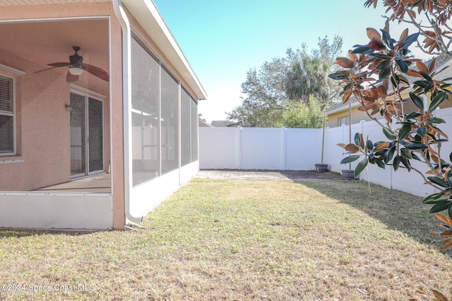 view of yard featuring a sunroom and ceiling fan