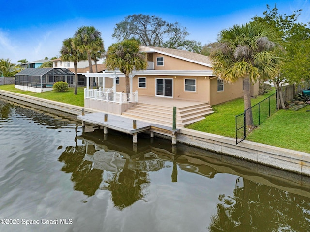 back of house featuring a lanai, a deck with water view, and a lawn