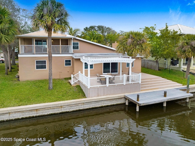 back of house featuring a pergola, a balcony, a water view, and a lawn