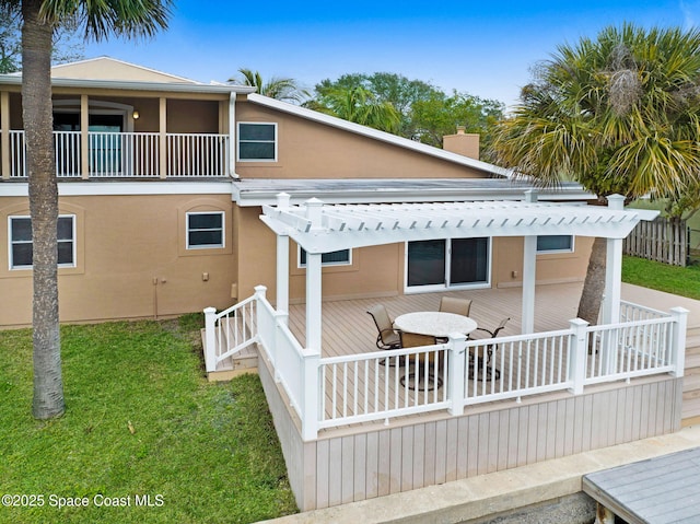 rear view of property with a pergola, a deck, and a yard