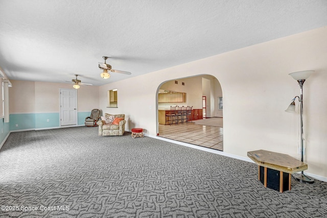 interior space featuring a textured ceiling, ceiling fan, and carpet