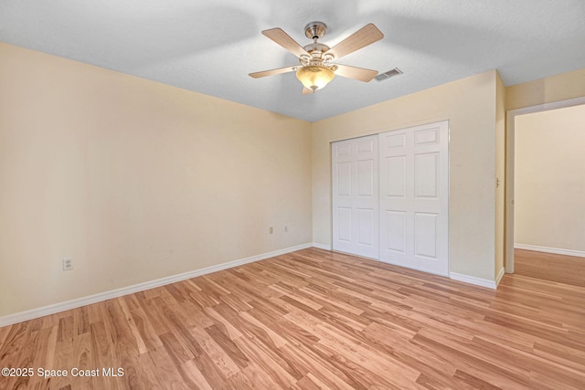 unfurnished bedroom featuring a textured ceiling, ceiling fan, a closet, and light hardwood / wood-style flooring