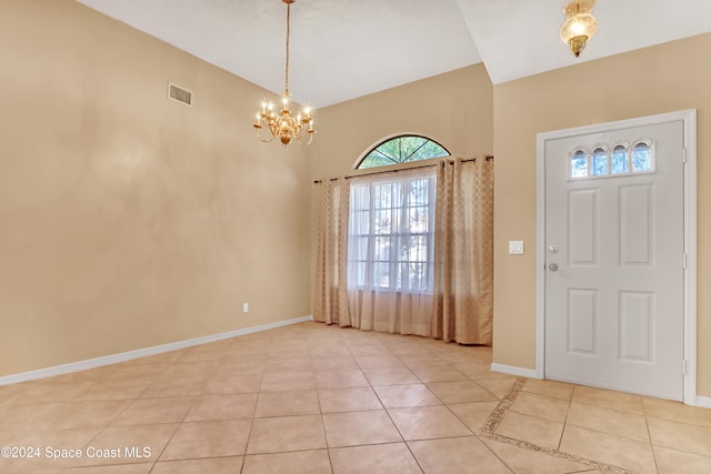 entrance foyer with light tile patterned flooring, vaulted ceiling, and an inviting chandelier