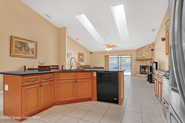 kitchen featuring ceiling fan, dishwasher, sink, a fireplace, and light tile patterned floors