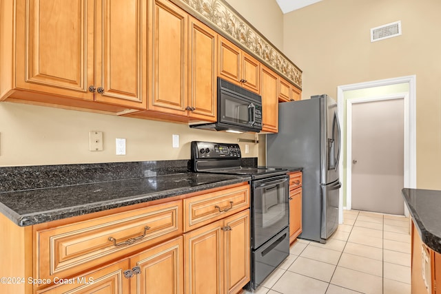 kitchen with light tile patterned flooring, dark stone counters, and black appliances