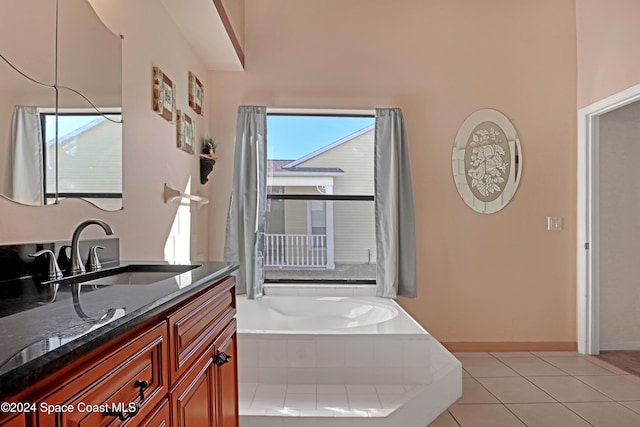 bathroom with vanity, tile patterned floors, a wealth of natural light, and tiled tub