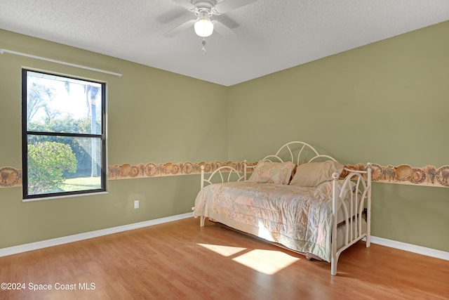 bedroom featuring ceiling fan, wood-type flooring, and a textured ceiling