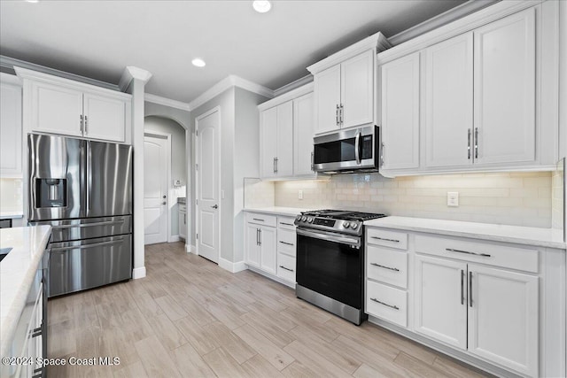 kitchen featuring light stone countertops, appliances with stainless steel finishes, ornamental molding, white cabinets, and light hardwood / wood-style floors