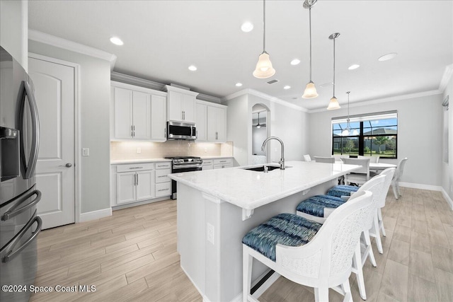 kitchen featuring white cabinetry, sink, stainless steel appliances, an island with sink, and pendant lighting