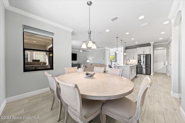 dining area with light hardwood / wood-style floors, ceiling fan, crown molding, and sink