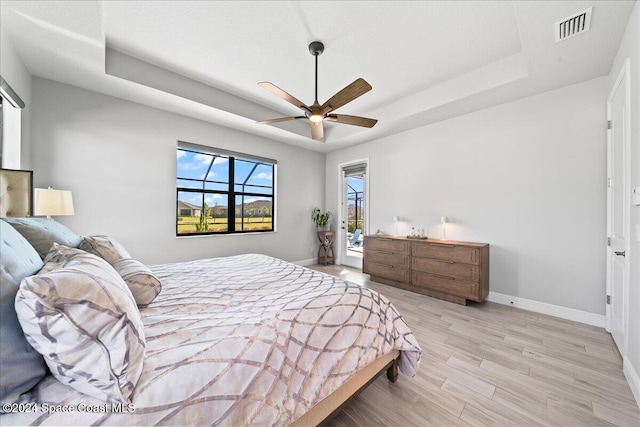 bedroom featuring a tray ceiling, ceiling fan, and light hardwood / wood-style flooring