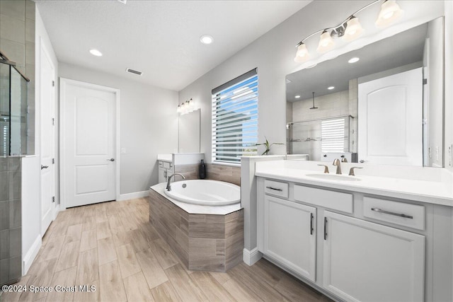 bathroom featuring wood-type flooring, vanity, and shower with separate bathtub