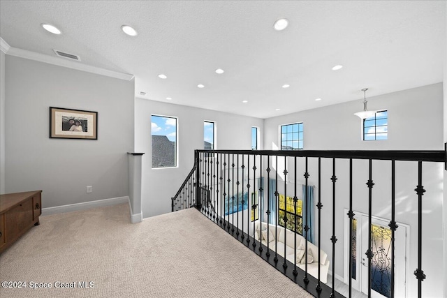 corridor with carpet flooring, a healthy amount of sunlight, crown molding, and a textured ceiling