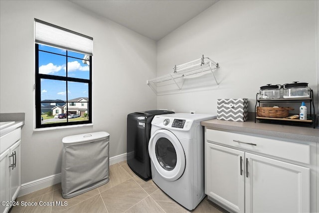 washroom with cabinets, light tile patterned floors, and washer and clothes dryer