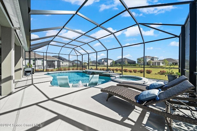 view of pool featuring glass enclosure, a patio area, and an in ground hot tub