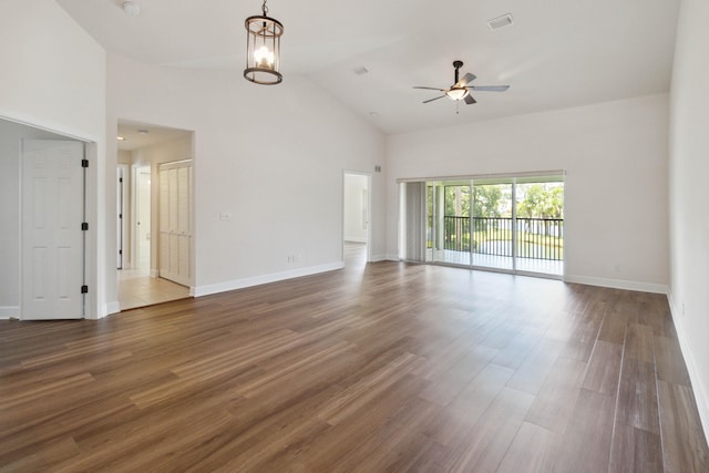 unfurnished living room with ceiling fan with notable chandelier, dark hardwood / wood-style flooring, and high vaulted ceiling