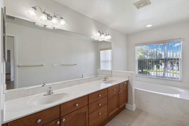 bathroom featuring tile patterned flooring, vanity, a tub to relax in, and a textured ceiling