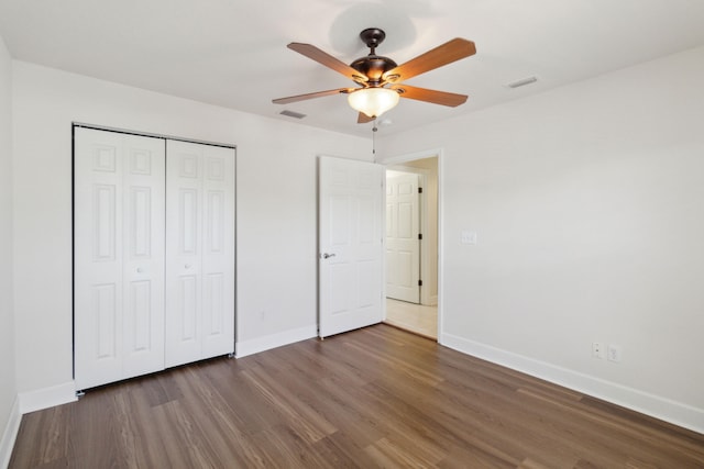 unfurnished bedroom featuring ceiling fan, a closet, and dark wood-type flooring