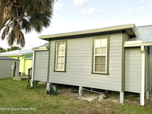 view of side of home with a storage unit and a yard