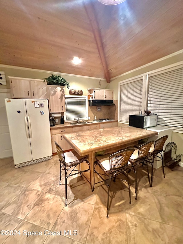 dining space featuring lofted ceiling with beams, sink, and wooden ceiling