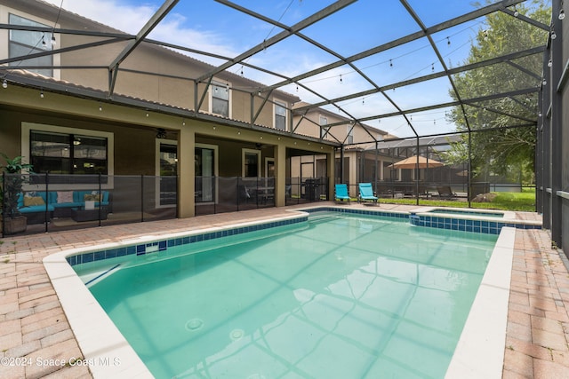 view of swimming pool featuring glass enclosure, ceiling fan, a patio area, and an outdoor hangout area