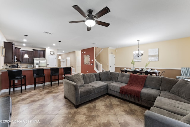 living room featuring ceiling fan with notable chandelier, dark tile patterned floors, and sink