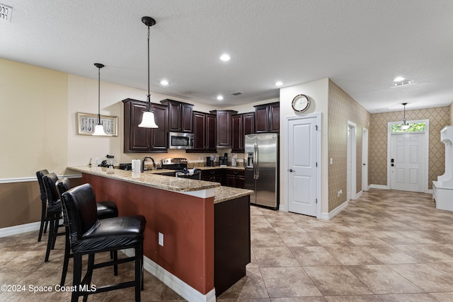 kitchen with kitchen peninsula, appliances with stainless steel finishes, a textured ceiling, and pendant lighting