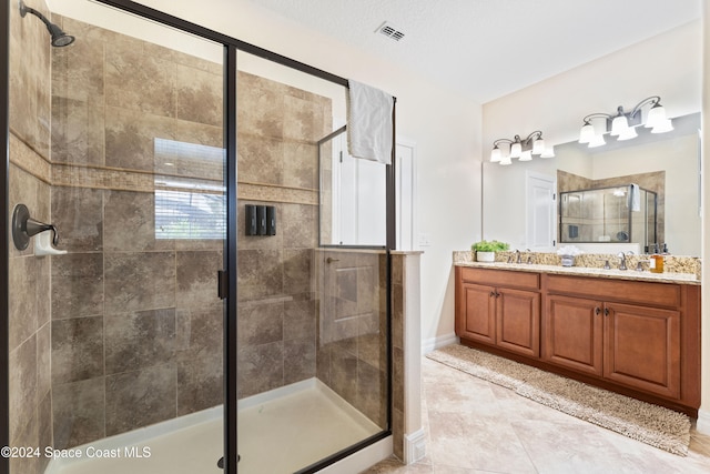 bathroom featuring tile patterned floors, vanity, an enclosed shower, and a textured ceiling