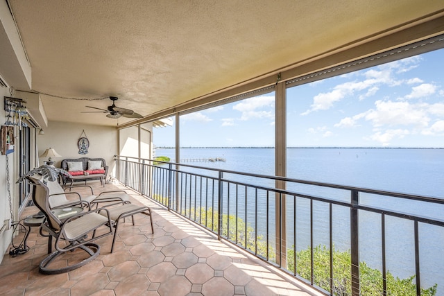 sunroom / solarium featuring ceiling fan and a water view