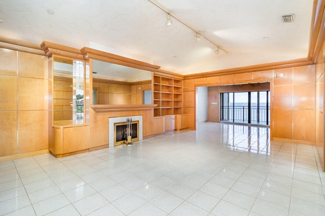 unfurnished living room with tile patterned floors, vaulted ceiling, built in features, and track lighting