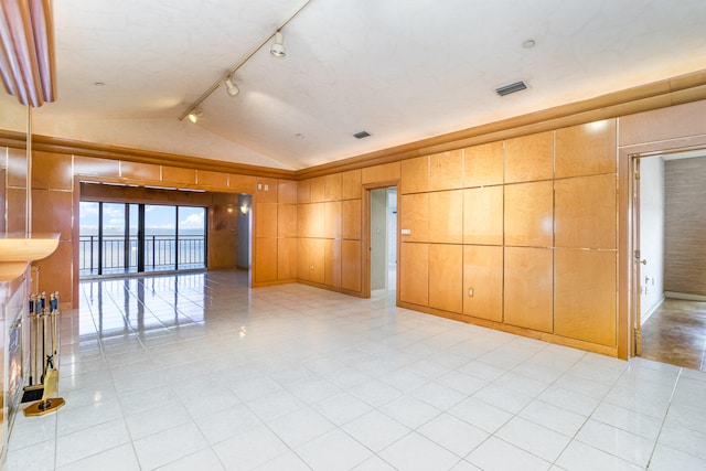 unfurnished room featuring rail lighting and lofted ceiling