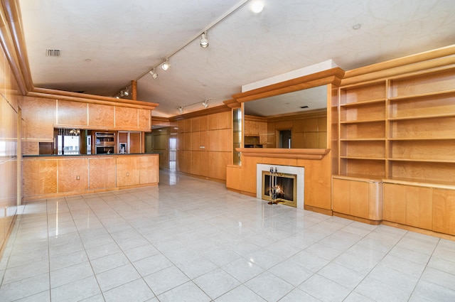 unfurnished living room with light tile patterned floors, track lighting, and a tiled fireplace