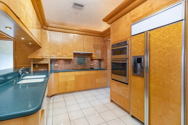 kitchen featuring backsplash, double oven, sink, light tile patterned floors, and paneled built in fridge