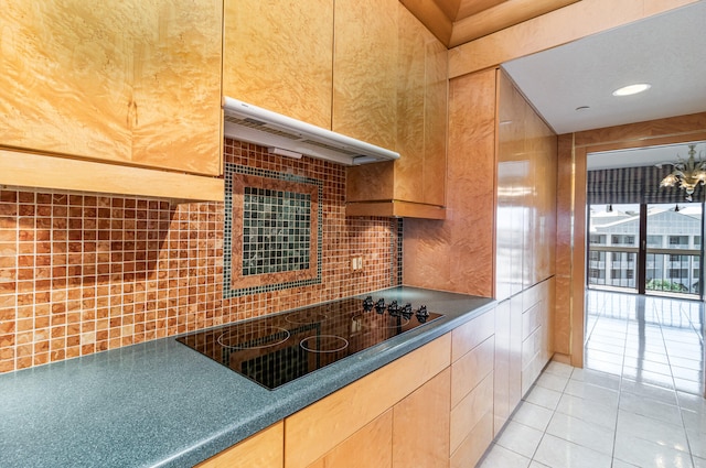 kitchen featuring light tile patterned floors, backsplash, black electric cooktop, and range hood