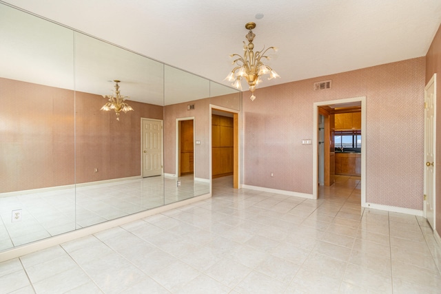 tiled empty room featuring a chandelier