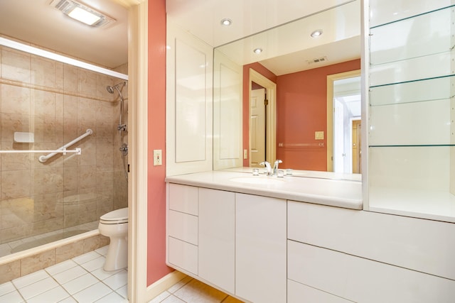 bathroom with tile patterned floors, vanity, a tile shower, and toilet