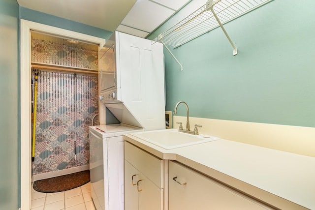 laundry area with cabinets, sink, light tile patterned floors, and stacked washer and dryer