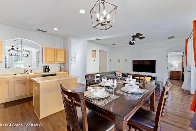 dining space with a textured ceiling, ceiling fan with notable chandelier, dark wood-type flooring, and sink