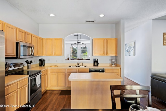 kitchen featuring hanging light fixtures, light brown cabinetry, dark wood-type flooring, and appliances with stainless steel finishes