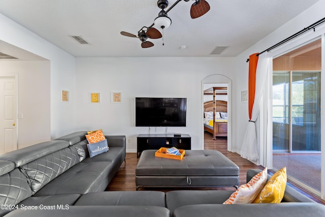 living room with a textured ceiling, dark hardwood / wood-style floors, and ceiling fan