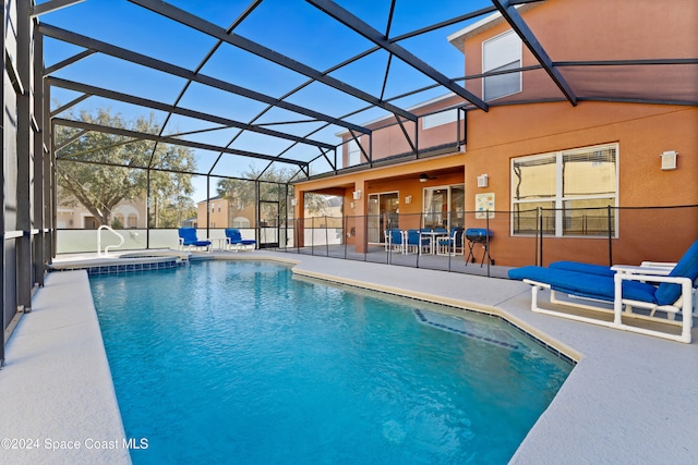 view of pool featuring glass enclosure, a patio area, and an in ground hot tub