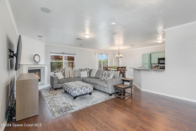 living room featuring ornamental molding, dark wood-type flooring, and a notable chandelier