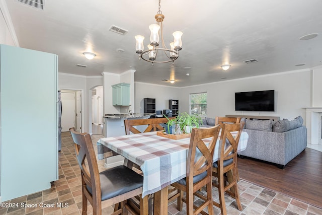 dining area with wood-type flooring, an inviting chandelier, and ornamental molding