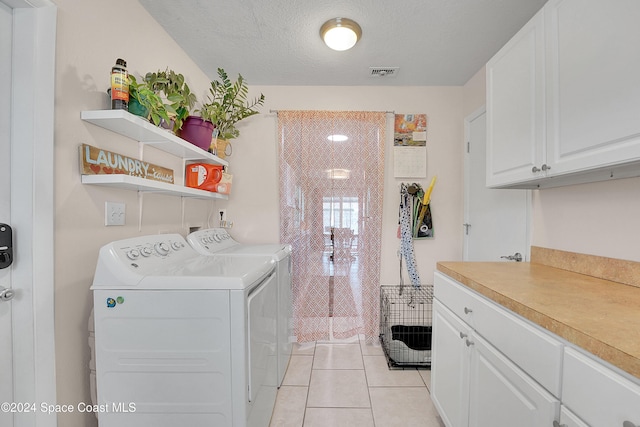 washroom featuring light tile patterned flooring, cabinets, independent washer and dryer, and a textured ceiling