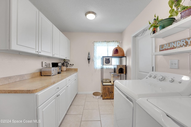 laundry room with washer and dryer, light tile patterned flooring, cabinets, and a textured ceiling