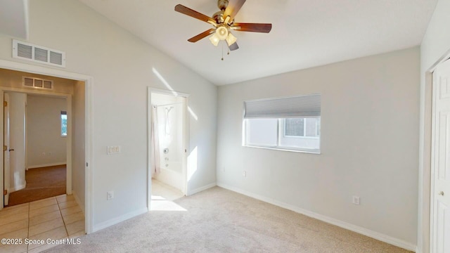 unfurnished bedroom featuring ensuite bathroom, light colored carpet, vaulted ceiling, ceiling fan, and a closet