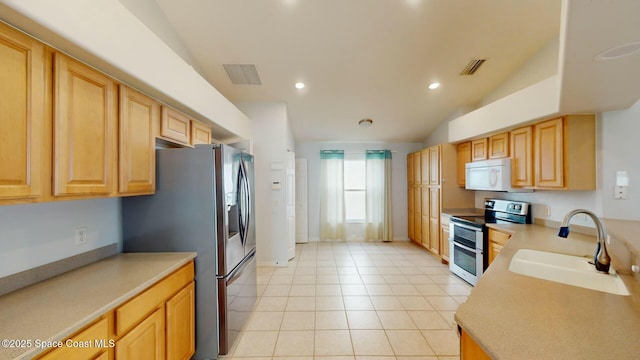 kitchen with light brown cabinets, sink, lofted ceiling, light tile patterned floors, and appliances with stainless steel finishes