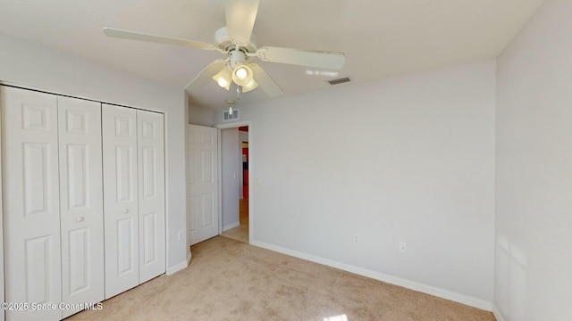 unfurnished bedroom featuring ceiling fan, a closet, and light carpet