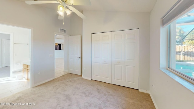 unfurnished bedroom featuring ceiling fan, a closet, light colored carpet, and lofted ceiling